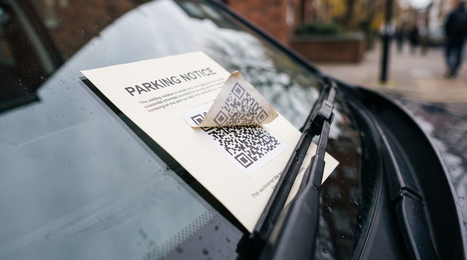 Vytištěná parkovací известка pod stěrkou na okně, druhá QR nálepka částečně přelepená přes původní kód